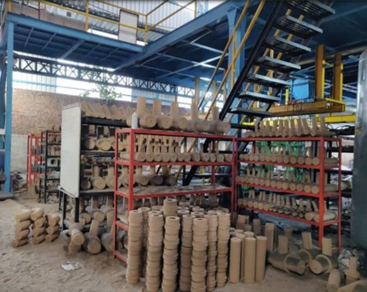 Sand cores of many sizes stacked on red racks and on the floor of the foundry